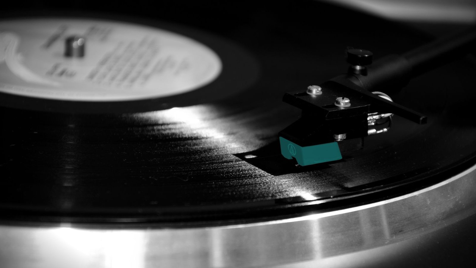 Close-up de um toca-discos analógico com braço posicionado sobre um disco de vinil em rotação