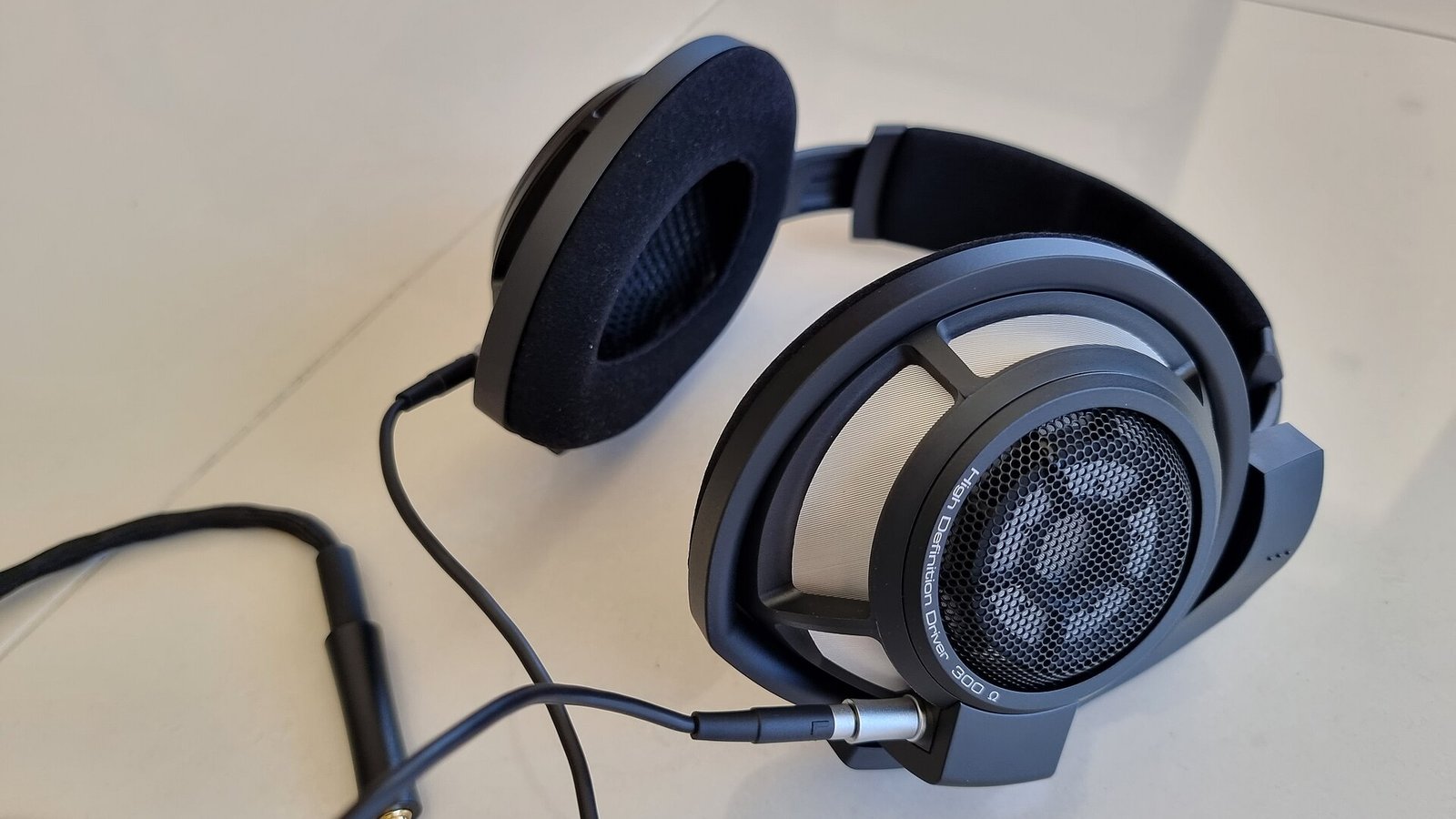 História da Sennheiser: fone de ouvido Sennheiser HD 650, modelo de alta definição com driver de 58 ohms, sobre superfície branca, fio com conector 3,5mm, detalhes visíveis da grade e almofadas