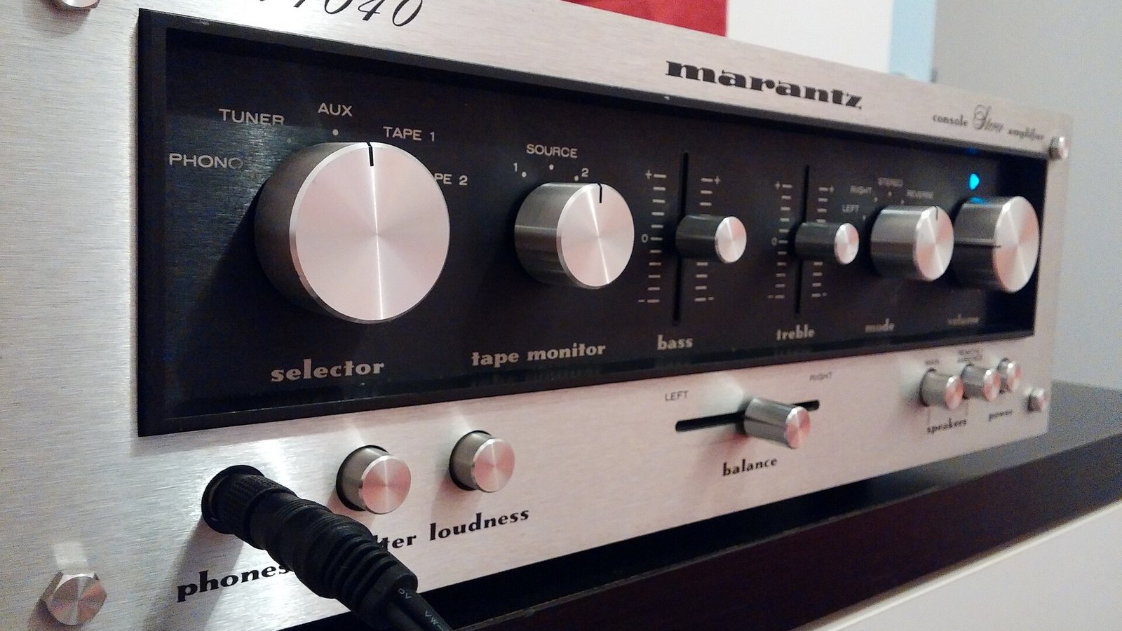 História da Marantz: amplificador Marantz Model 1040, em acabamento metálico com painel de controle analógico, mostrando botões e controles como selector, tape monitor, bass, treble, balance e entrada