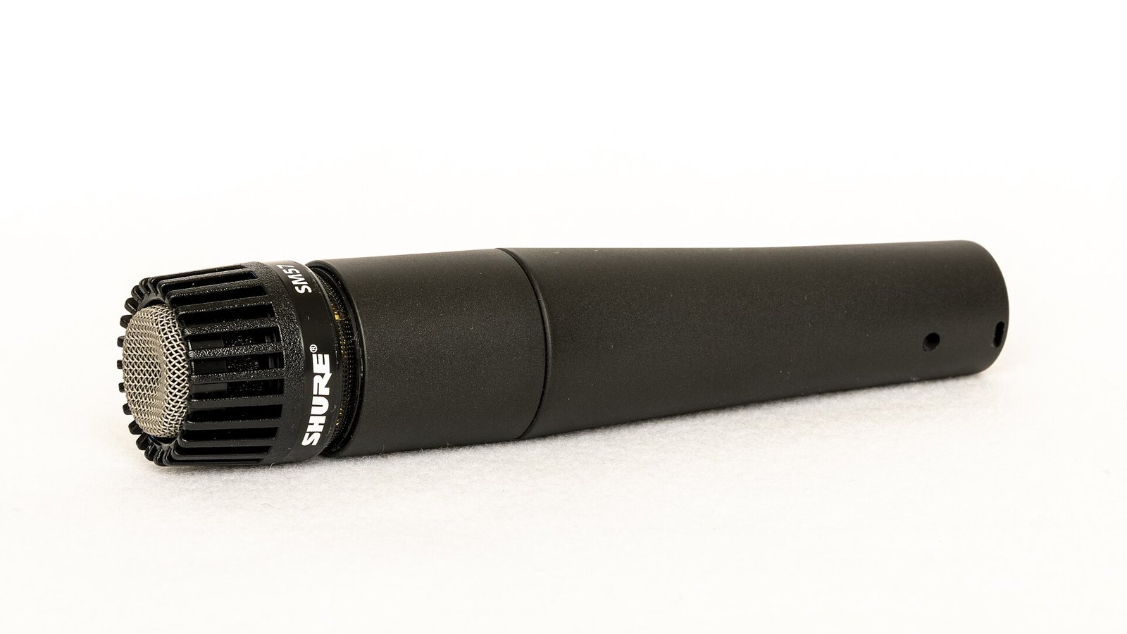História da Shure: microfone Shure SM58 preto, foto real em fundo branco, mostrando o produto inteiro e em foco, com logotipo visível na base da grade