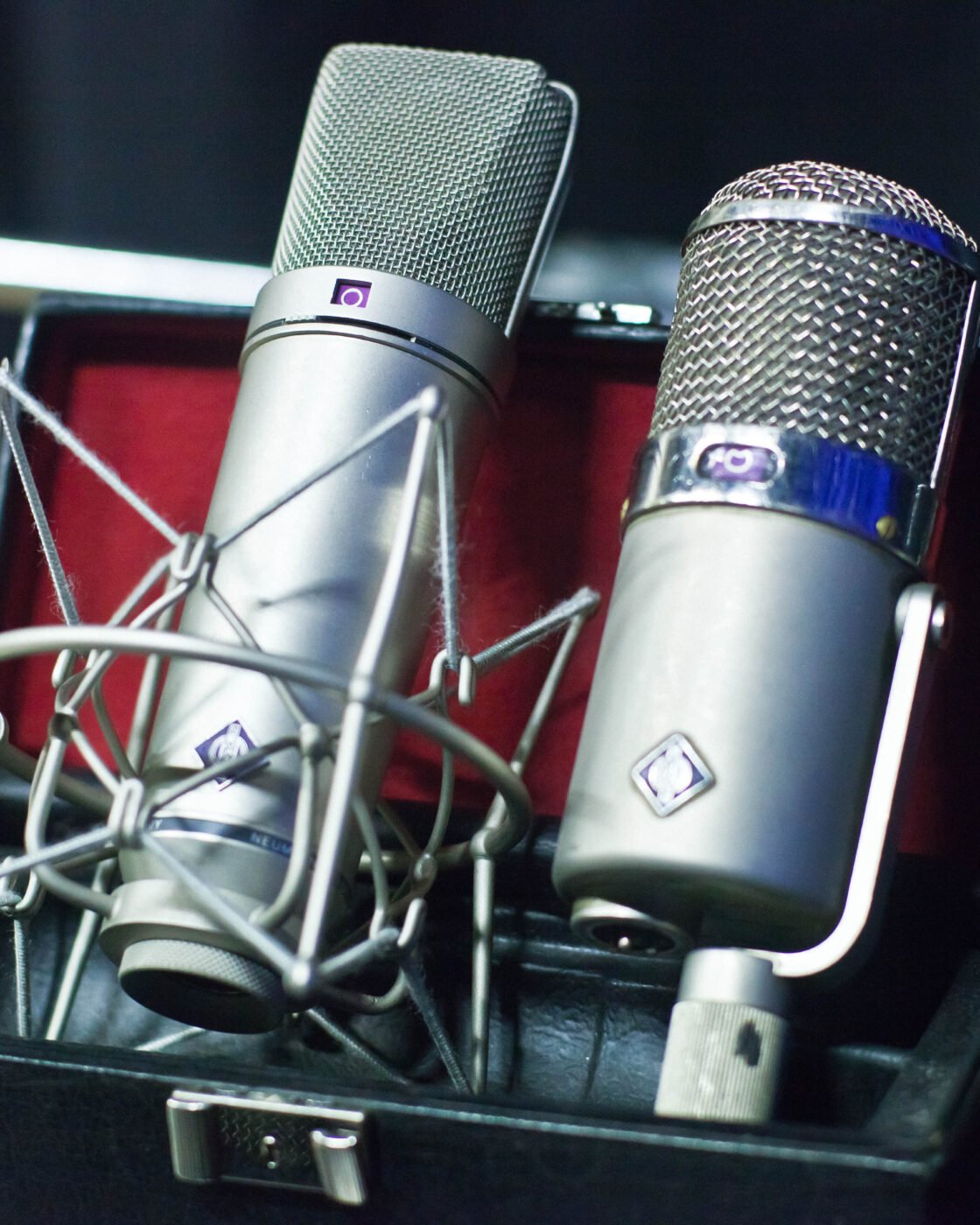 Microfones condensadores Neumann U 87 e U 47 montados lado a lado em pedestais em um estúdio de gravação