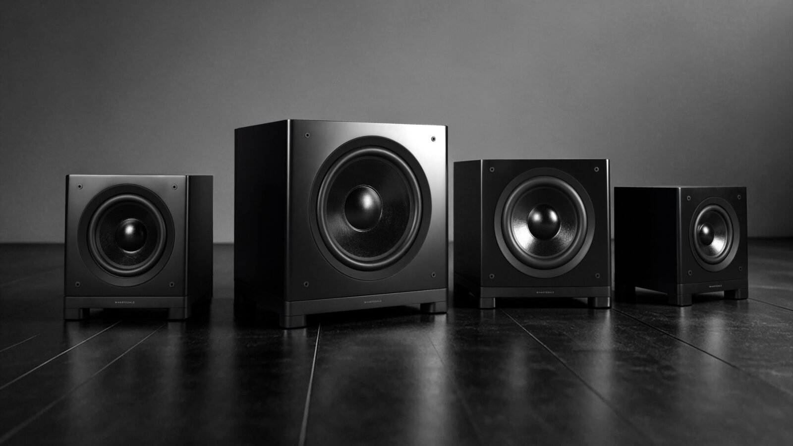 Subwoofers da série Wharfedale Nova em acabamento preto fosco, em quatro tamanhos lado a lado