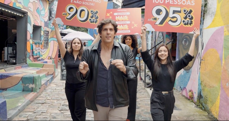 Rafael Infante e participantes no Beco do Batman, em São Paulo, com placas da campanha 11.11 do AliExpress "Quanto Mais Amigos, Mais Desconto"