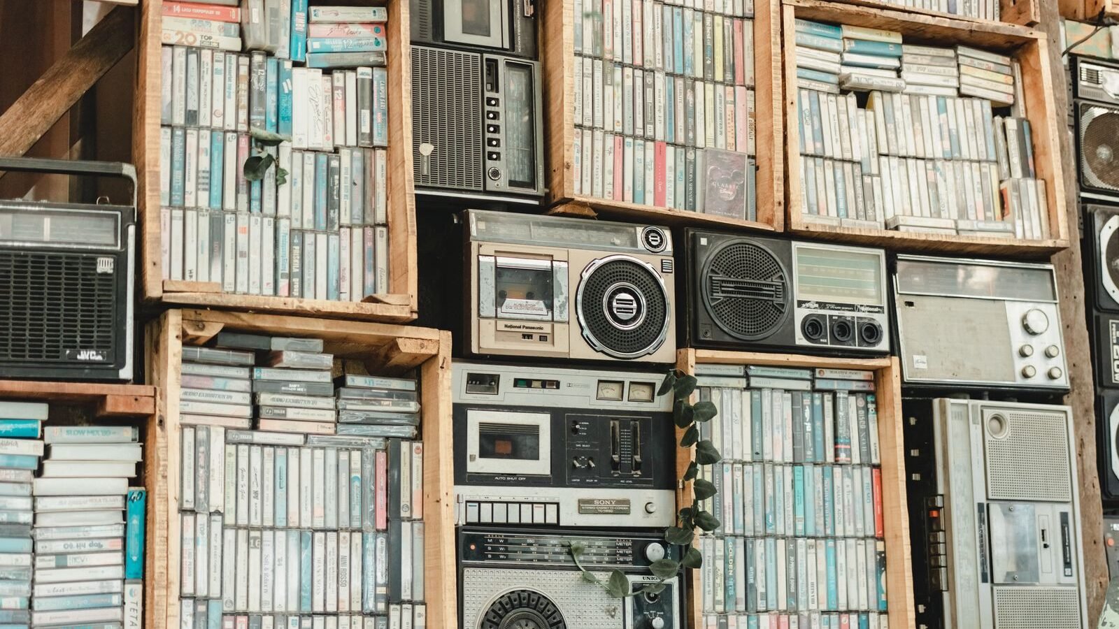 Estantes de madeira com centenas de fitas cassete e aparelhos de som antigos com tape decks