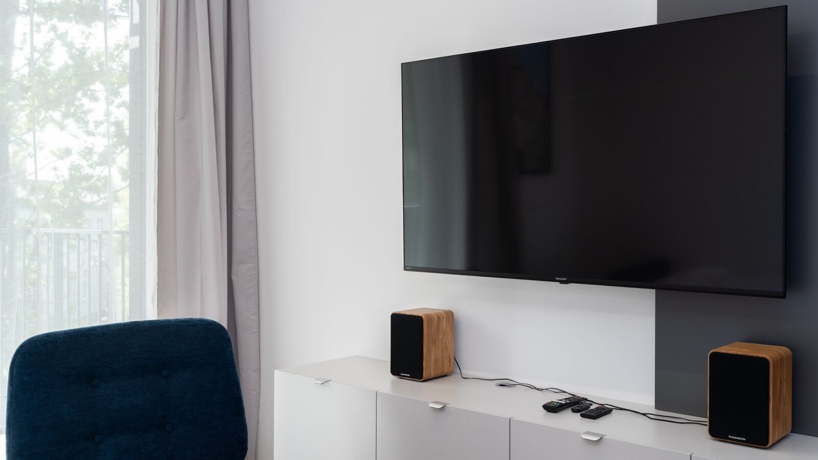 TV de tela plana na parede com um par de caixas bookshelf de madeira sobre o rack da sala
