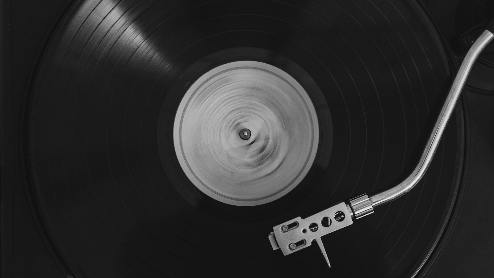 Disco de vinil girando em toca-discos visto de cima, com o braço e a agulha sobre o sulco
