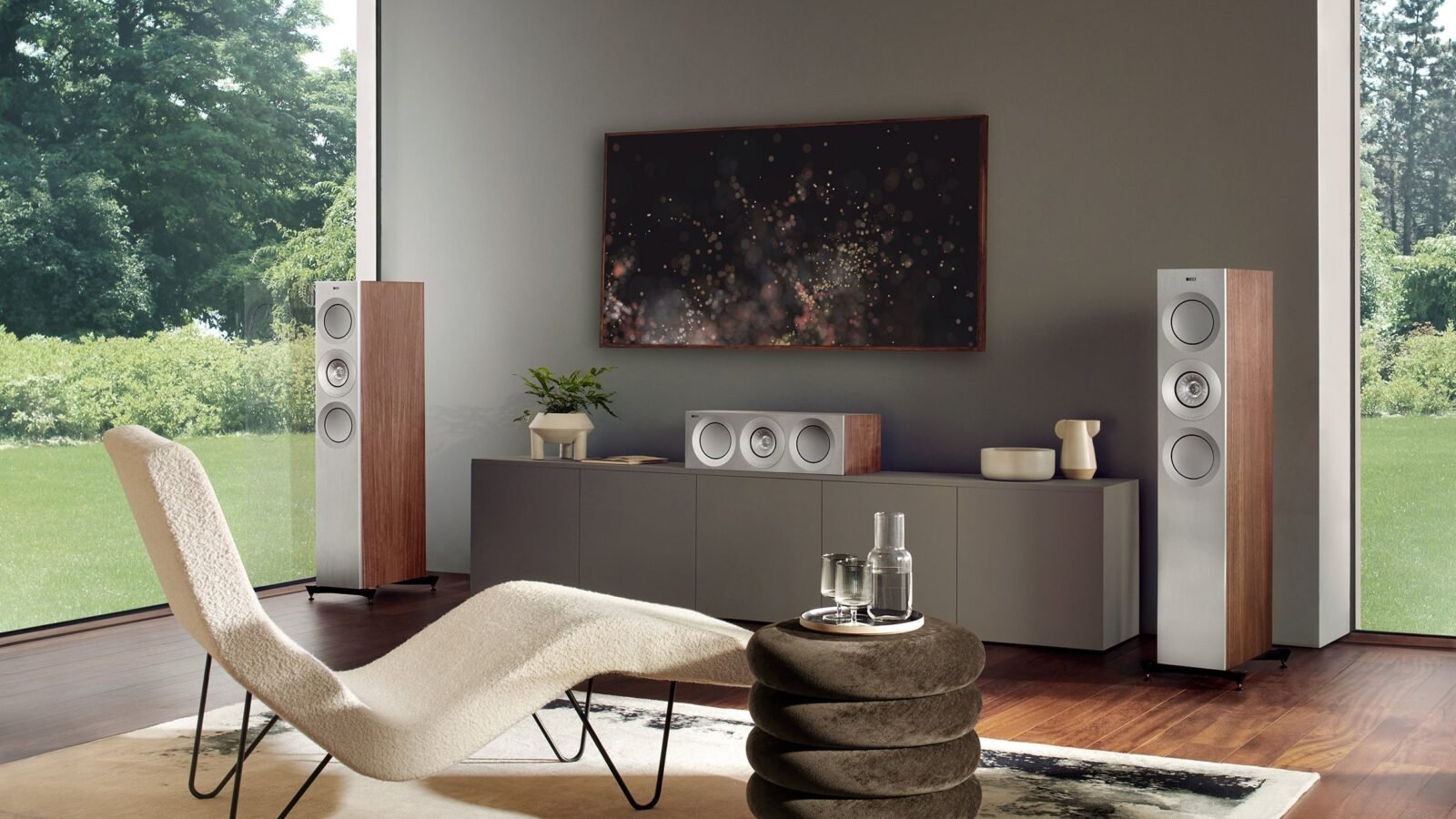 Par de caixas torre KEF Reference em sala de estar, afastadas da parede e simétricas em relação à TV e ao móvel central