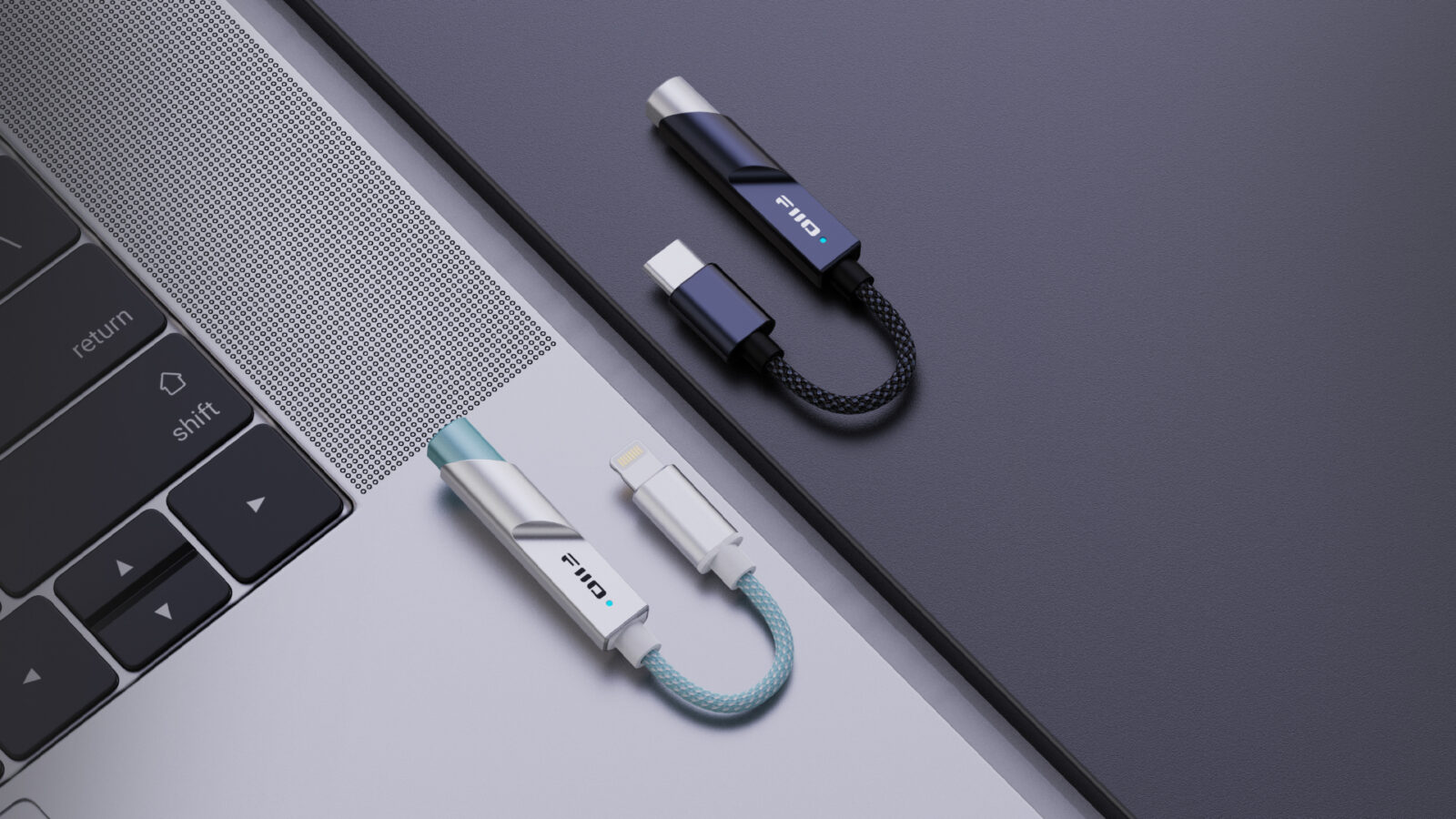 Dongles FiiO KA11 nas versões USB-C preta e Lightning prata sobre um notebook