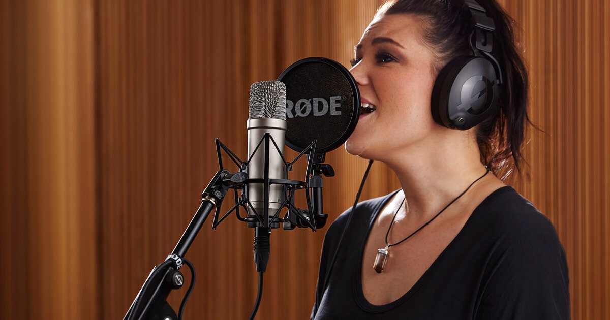 Cantora gravando voz em estúdio com microfone condensador Rode NT1-A em suspensão e pop filter