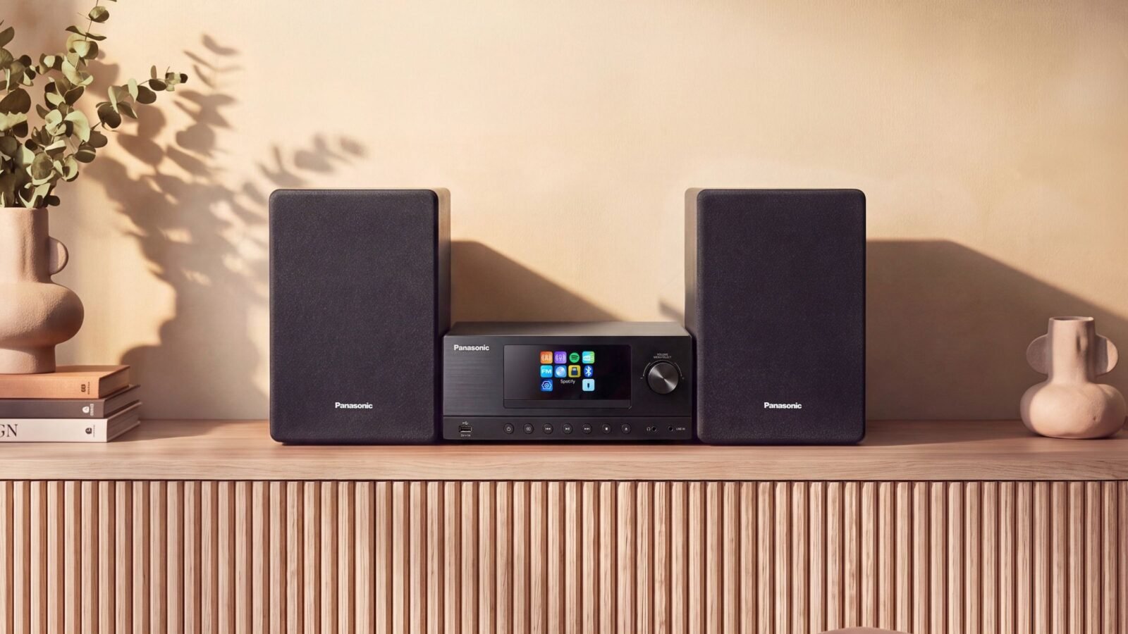 Micro system Panasonic SC-PMX112 preto com tela colorida e duas caixas de som sobre um aparador de madeira