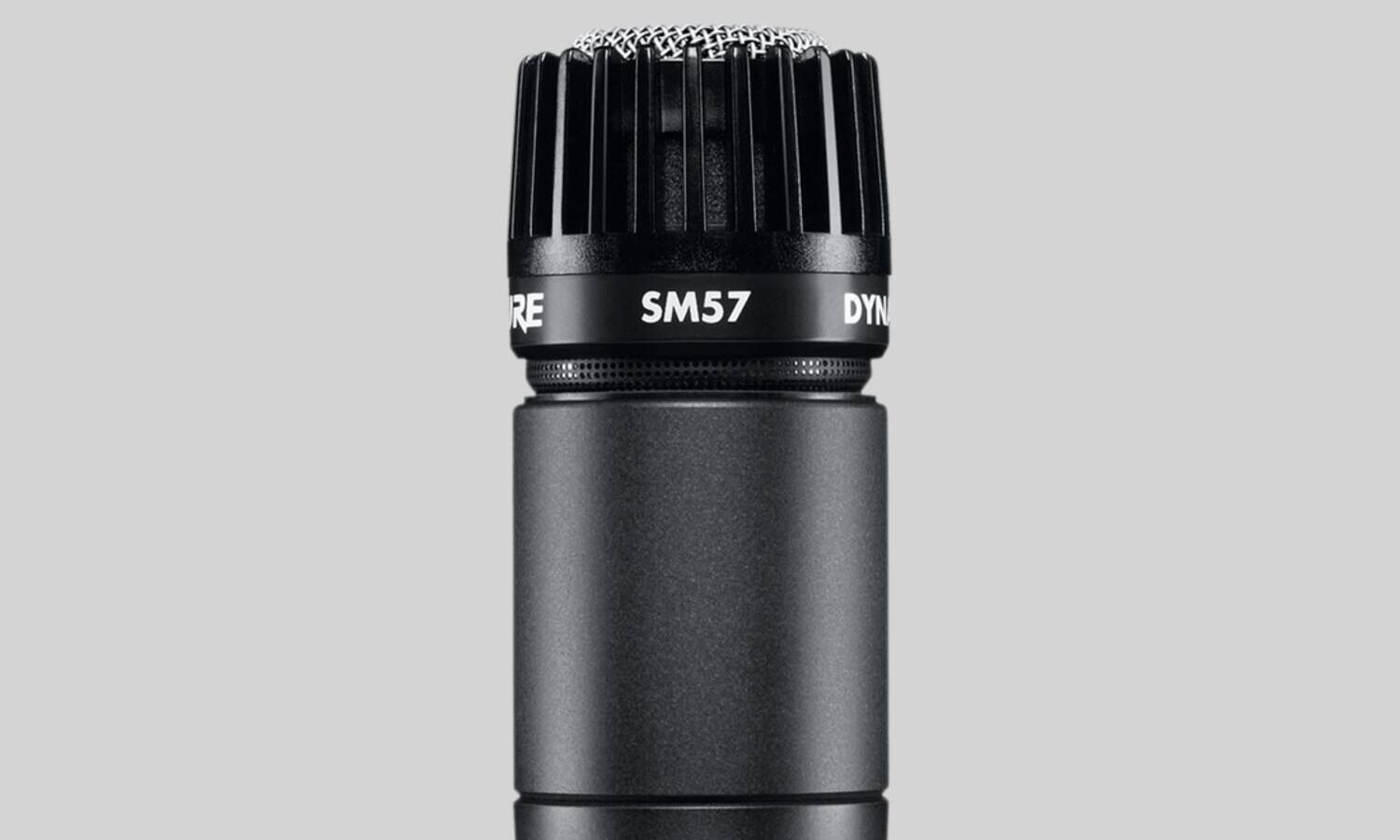 Microfone dinâmico Shure SM57 preto com grade metálica, visto de lado sobre fundo branco