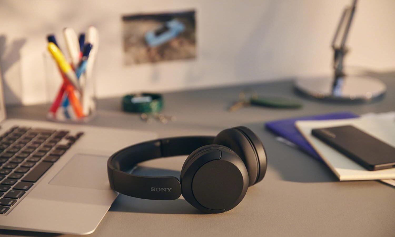 Headphone Sony WH-CH520 preto sobre mesa ao lado de um notebook