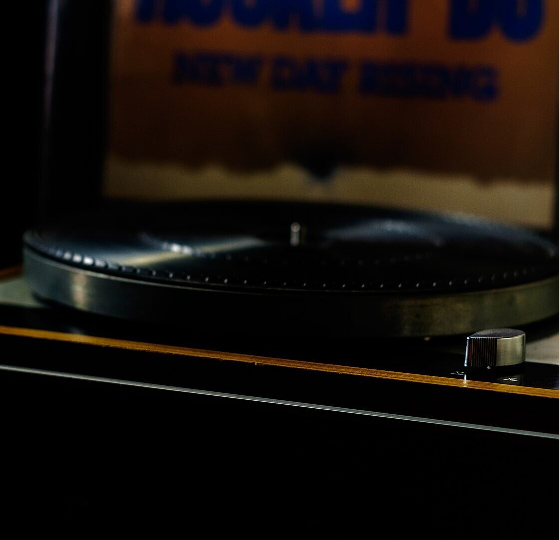 Toca-discos Thorens TD 160 com plinto de madeira, braço com cápsula e disco de vinil no prato, fotografado em ambiente escuro